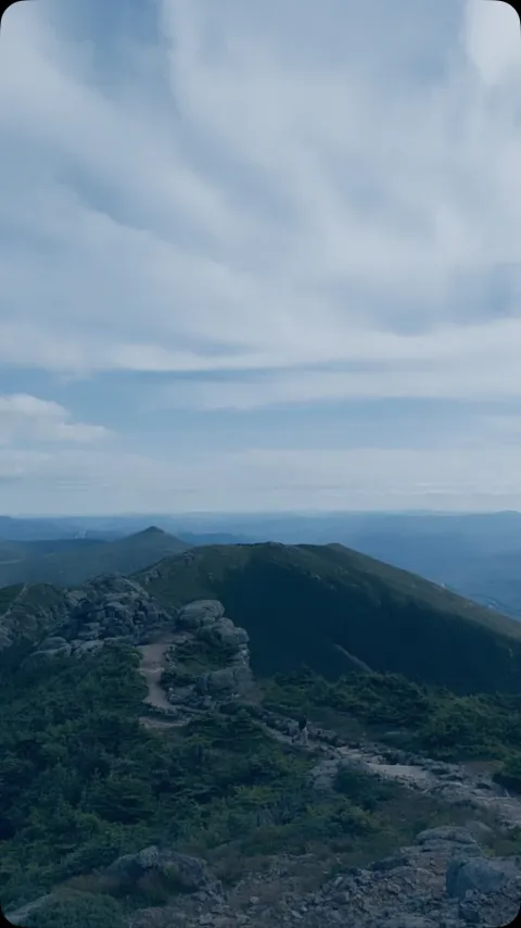 A green mountain ridge beneath a cloudy sky.