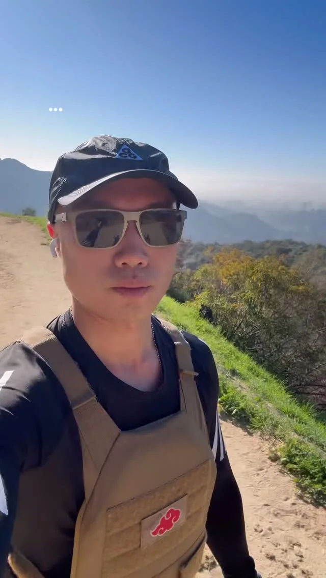 A hiker in a cap and sunglasses on a mountain trail.