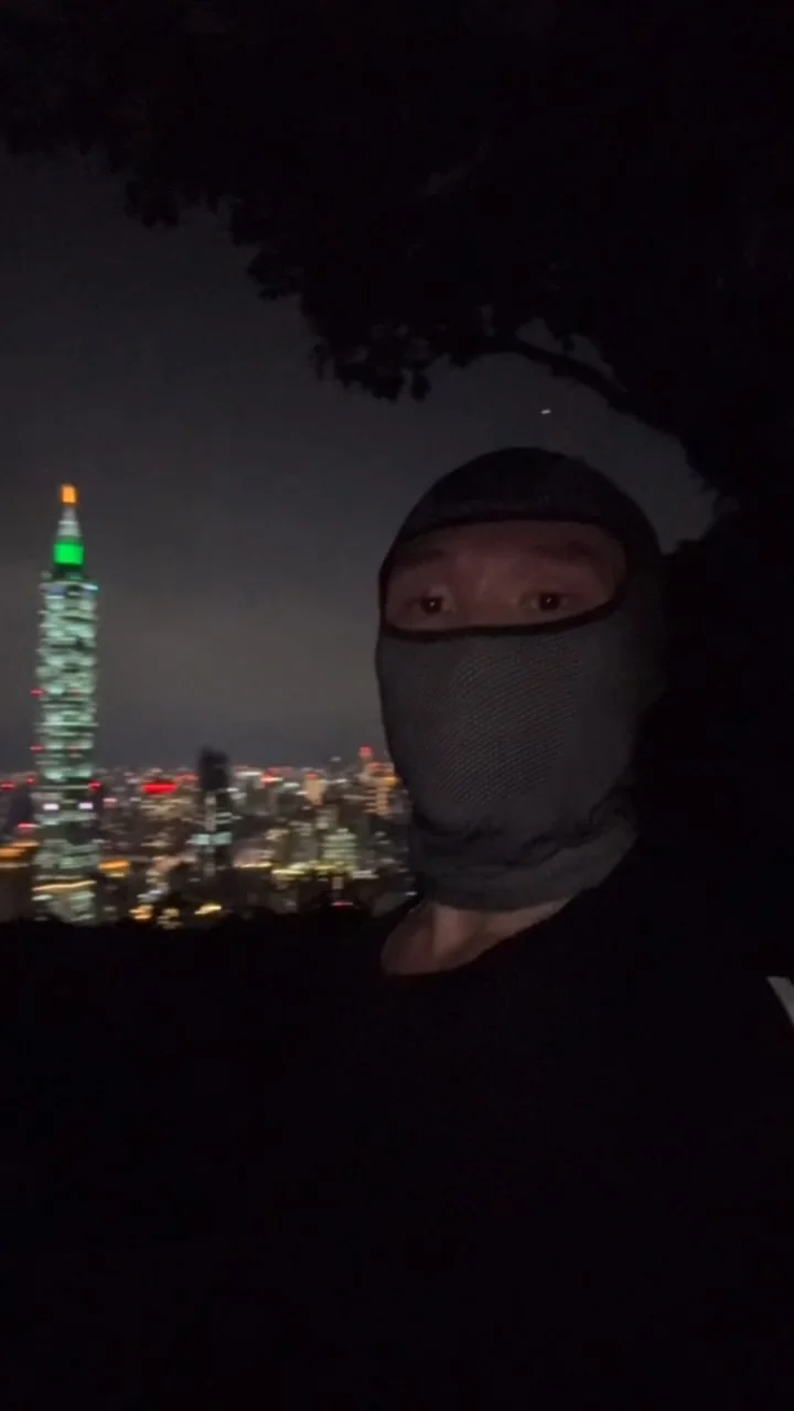 A person in a face covering overlooking a city at night.